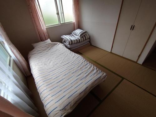 Habitación pequeña con cama y ventana en メゾンドヴィラ en Kami-furano
