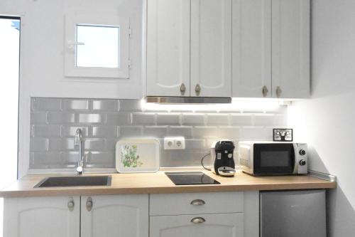 a kitchen with white cabinets and a sink and a microwave at CAPILLITA XXI APARTAMENTOS in Sanlúcar de Barrameda