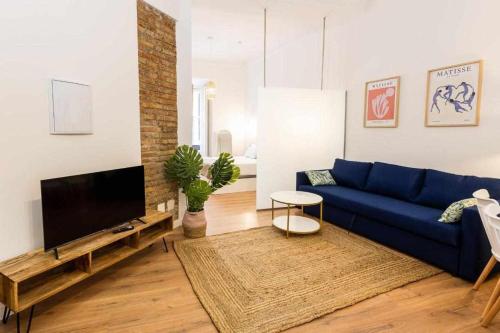 sala de estar con sofá azul y TV en Strachan Apartamentos en el corazón de Málaga, en Málaga