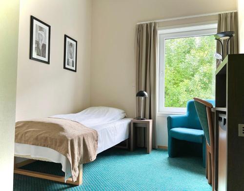 um quarto com uma cama, uma cadeira e uma janela em Ryfylke Fjordhotel em Sand