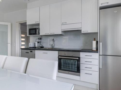 a kitchen with white cabinets and white appliances at Holiday Home Villa hirvas by Interhome in Salmentaka