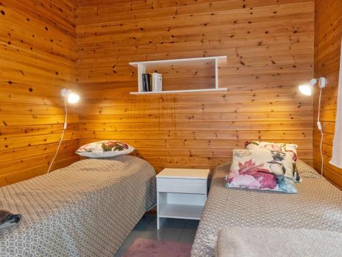 two beds in a room with wooden walls at Holiday Home Mäkitupa by Interhome in Syöte