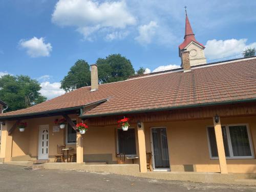 un edificio con un campanario con flores rojas. en Bátorka Vendégház, en Tállya