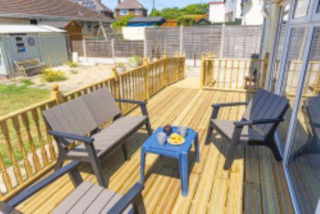 a deck with two benches and a blue table at Lanehouse Rocks in Weymouth