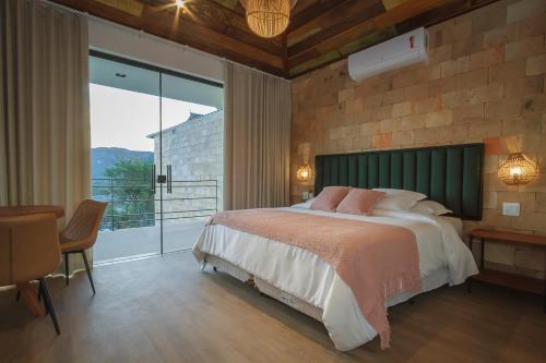 a bedroom with a large bed and a large window at Solar Da Serra Tiradentes in Tiradentes