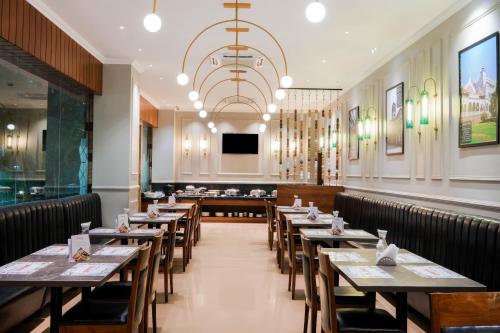 a dining room with tables and chairs and a chandelier at 7 Apple Hotel - Viman Nagar Pune in Pune