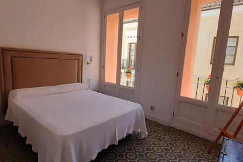 a bedroom with a white bed and two windows at Tu alojamiento en Cáceres in Cáceres