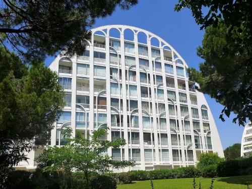 un edificio alto y blanco con árboles delante en Apartment Les Jardins du Couchant by Interhome en La Grande-Motte