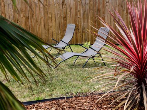 deux chaises assises dans une cour à côté d'une clôture dans l'établissement Holiday Home La Villa Dorée by Interhome, à Pornic