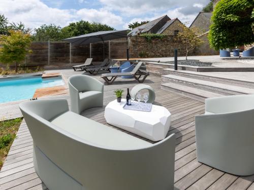 eine Terrasse mit weißen Möbeln neben einem Pool in der Unterkunft Holiday Home La Gentilhommière by Interhome in Le Tronchet