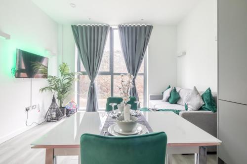 a living room with a white table and green chairs at Elegant apartment in Milton Keynes