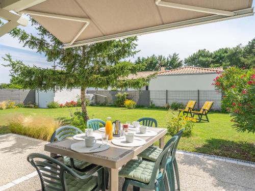 a wooden table and chairs on a patio at Holiday Home Villa Margarin by Interhome in Les Mathes