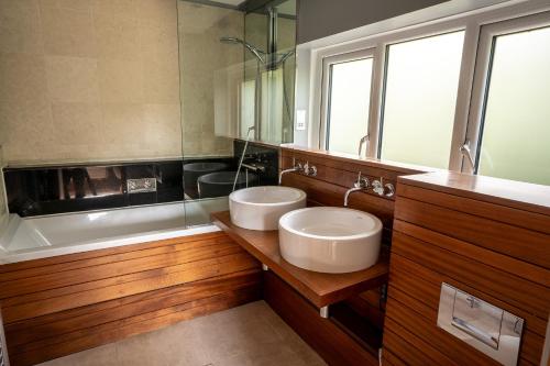 a bathroom with two sinks and a bath tub at Maes Yr Haf in Swansea
