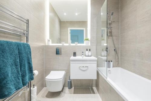 a bathroom with a toilet and a tub and a sink at Elegant apartment in Milton Keynes