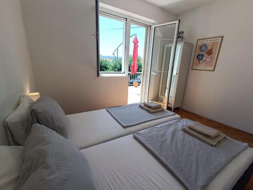 a bedroom with two beds and a large window at Holiday House Oleas Stari Grad Hvar sunny terrace and 2 min to ocean and center in Stari Grad