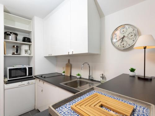een keuken met een wastafel en een klok aan de muur bij Apartment Saint Sieu by Interhome in Lancieux