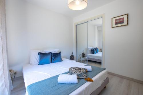 een slaapkamer met een bed met blauwe kussens en een spiegel bij Spacieux appartement de 70 m2, 2 chambres, au calme proche du Vieil Antibes in Antibes