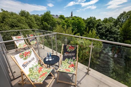 einen Balkon mit zwei Stühlen und einem Tisch darauf in der Unterkunft Garden Square Hotel in Krakau