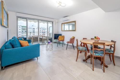 un salon avec un canapé bleu et une table dans l'établissement Juan Les Pins Two Bed Apt Beach Access, à Antibes