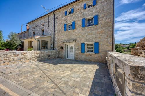 a large stone building with blue shutters on it at Casa Darel with Whirlpool in Vižinada