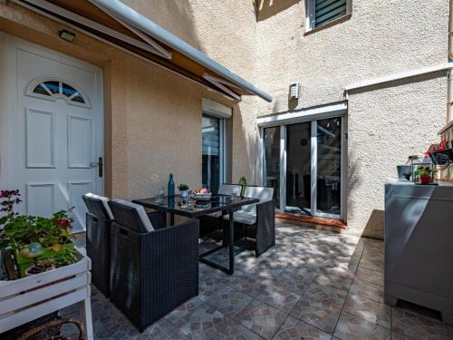 un patio avec une table et des chaises à côté d'un bâtiment dans l'établissement Apartment Les Cabestans 1-2-3-5 by Interhome, au Barcarès
