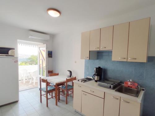 a kitchen with white cabinets and a table and a tableablish at Apartments Danica in Lopar