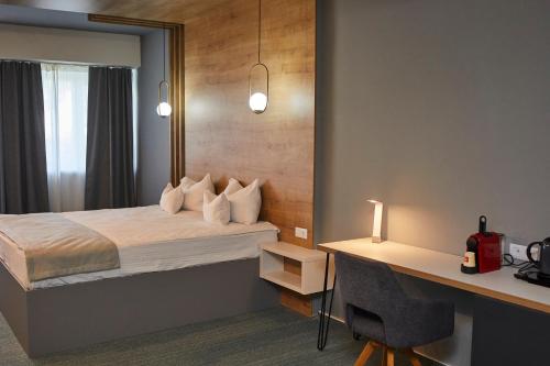 Hotel Bistrita في بيستريتسا: غرفة في الفندق مع سرير ومكتب مع مكتب
