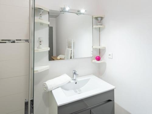 a white bathroom with a sink and a mirror at Apartment grand courlis by Interhome in Mimizan