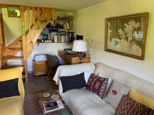 een woonkamer met een bank en een trap bij Apartment Village des Oursons Chalet A4 by Interhome in Chamonix-Mont-Blanc