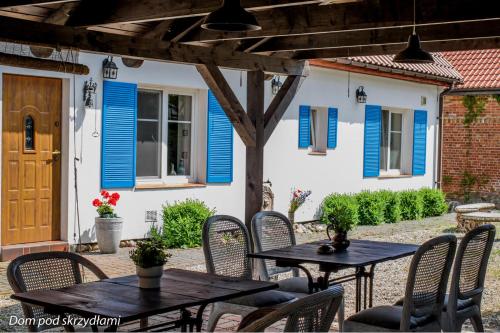 un patio con persianas azules en una casa con mesas y sillas en Dom pod Skrzydłami, en Gawliki Wielkie