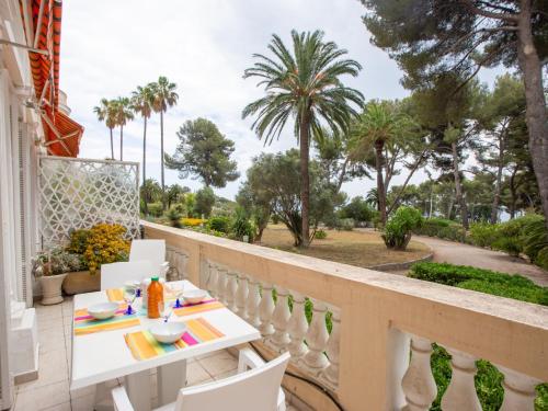 un balcon avec une table, des chaises et des palmiers dans l'établissement Apartment Mont des Oiseaux-3 by Interhome, à Hyères