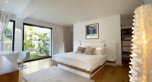 una camera da letto con un letto bianco e ampie finestre di Casa Tyane a Sant Jordi