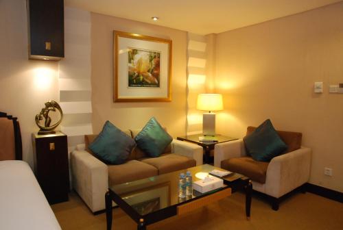 a living room with a couch and chairs in a hotel room at 东莞君兰酒店 Grand land hotel in Dongguan