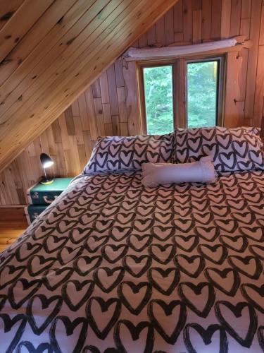 a large bed in a room with a wooden ceiling at Le petit chalet sur le lac in Sainte-Marguerite