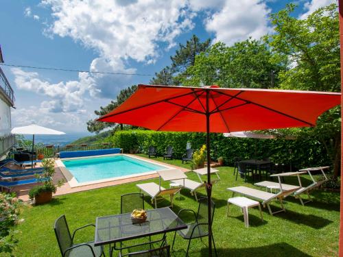 une terrasse avec un parasol rouge et une piscine dans l'établissement Apartment Matteo by Interhome, à Avaglio