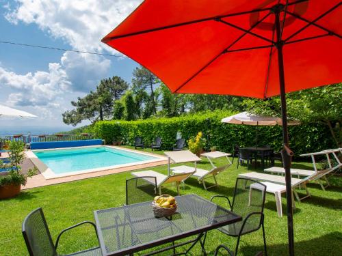 a red umbrella sitting on a table next to a pool at Apartment Matteo by Interhome in Avaglio