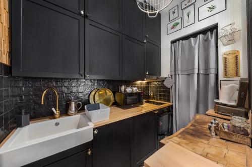 - une cuisine avec des placards noirs et un évier blanc dans l'établissement Les Petites Suites Dieppoises - La Demeure de Peau d'Ane, à Dieppe