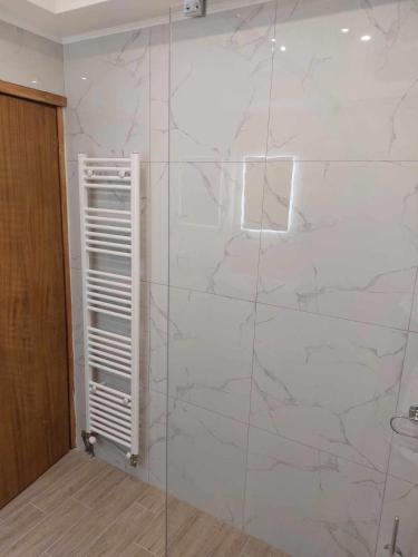 a bathroom with a glass shower with a white wall at Pablo Boutique Rooms in Néon Petrítsion