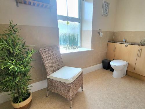 a bathroom with a toilet and a chair and a plant at Plymouth Hoe Central * Free Parking * Ocean Reach in Plymouth