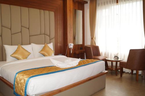 a bedroom with a large bed and a room with chairs at Hotel Varun Mansion Hassan in Hassan