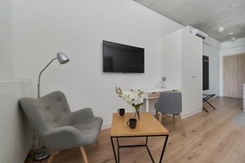 Una sala de estar con dos sillas y una mesa con televisión. en PIEKARNIA Żywa Kultura Atmospheric Apartments in Wrocław by Noclegi Renters, en Wroclaw