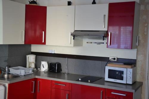 - une cuisine avec des placards rouges et blancs et un four micro-ondes dans l'établissement Pêcheur: F2 climatisé au cœur du village., à Palavas-les-Flots