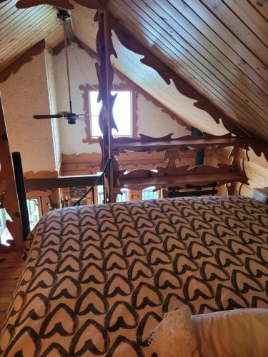 a large bed in a room with a wooden ceiling at Le petit chalet sur le lac in Sainte-Marguerite