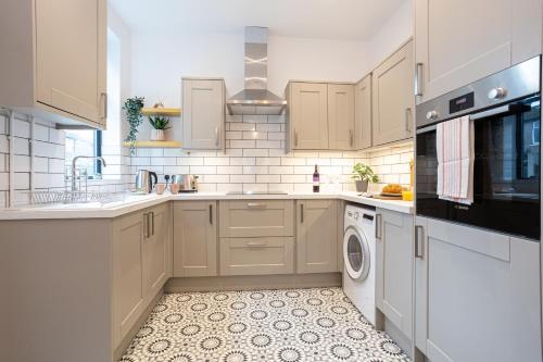 a kitchen with white cabinets and a washer and dryer at Stunning Scandi Abode in Manchester Parking in Manchester