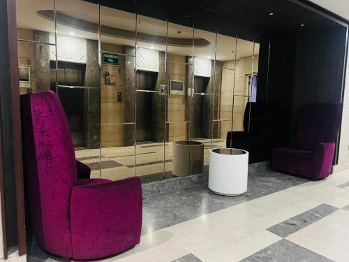 a room with two purple chairs and a glass wall at AVR HOTELS 1 BHK Rooms sapphire Mall 83 Manesr in Gurgaon