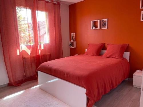 - une chambre rouge avec un lit avec des draps rouges et une fenêtre dans l'établissement Villa individuelle - CHASSIEU, à Chassieu