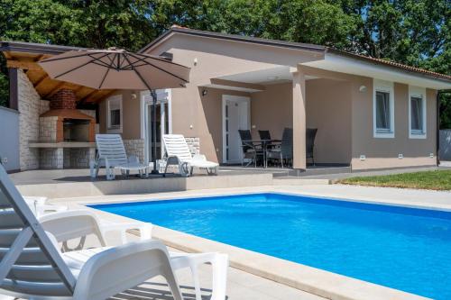 a swimming pool with chairs and an umbrella next to a house at Houses Trinetta in Valtura