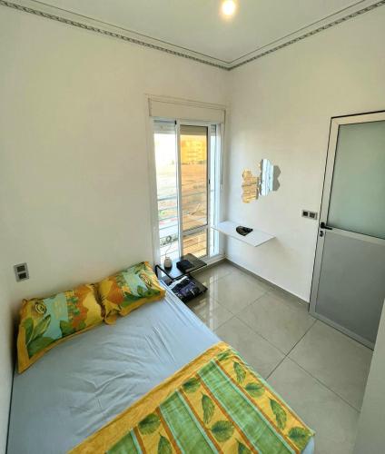 a bedroom with a bed and a large window at Appartement dans résidence à 2 pas de la mer et parking in Tangier