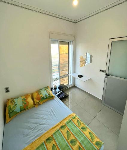 ein Schlafzimmer mit einem Bett und einem großen Fenster in der Unterkunft Appartement dans résidence à 2 pas de la mer et parking in Tangier