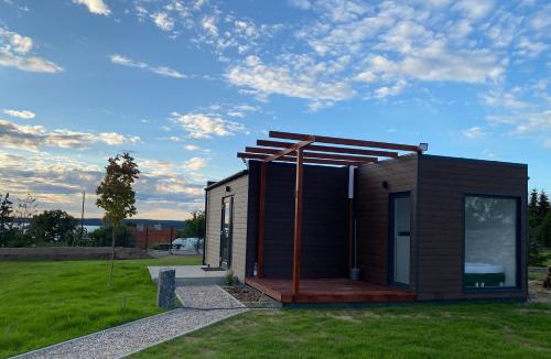 a small cabin with a deck on the grass at Domek nad jeziorem in Kruklanki